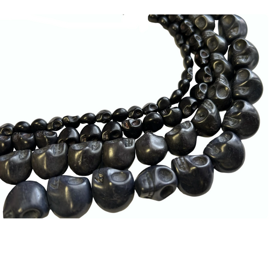 Black dyed howlite skull bead strands in assorted sizes arranged in overlapping curves on white.”