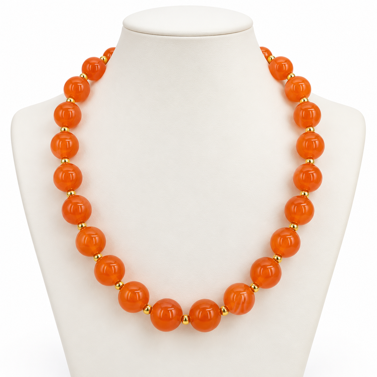 An orange beaded necklace displayed on a white mannequin bust. The necklace features large, polished round orange beads separated by small gold spacer beads.