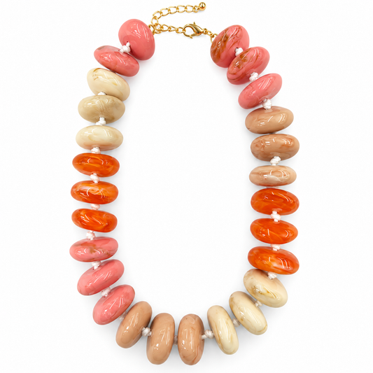 A beaded statement necklace featuring alternating rows of polished coral pink, orange, and beige marbled oval beads, secured with a gold-tone chain clasp on a white background.