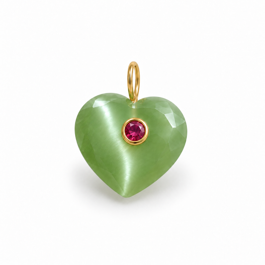 A heart-shaped pendant made of smooth light green stone with a small round pink gemstone in a gold bezel setting and a gold loop at the top, shown on a clean white background.