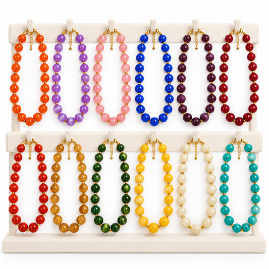 Twelve beaded necklaces in assorted vibrant colors, including orange, purple, pink, blue, red, brown, green, yellow, cream, and turquoise, displayed on a white two-tier jewelry stand.