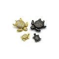 A collection of small cubic zirconia turtle beads on a surface