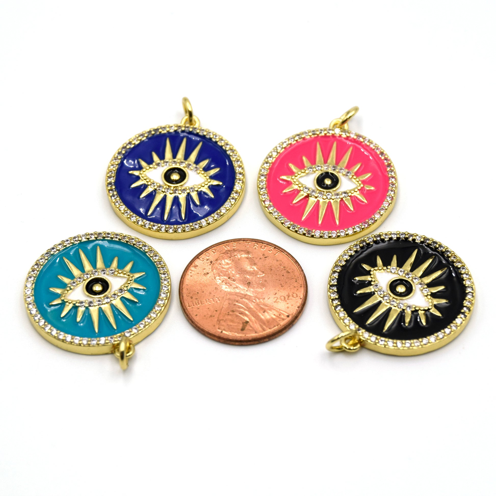 This photo features four intricately designed evil eye charms for jewelry making, next to a penny for size reference.