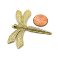  This photo shows a delicate gold dragonfly pendant with sparkling white cubic zirconia stones, placed next to a penny for size reference.