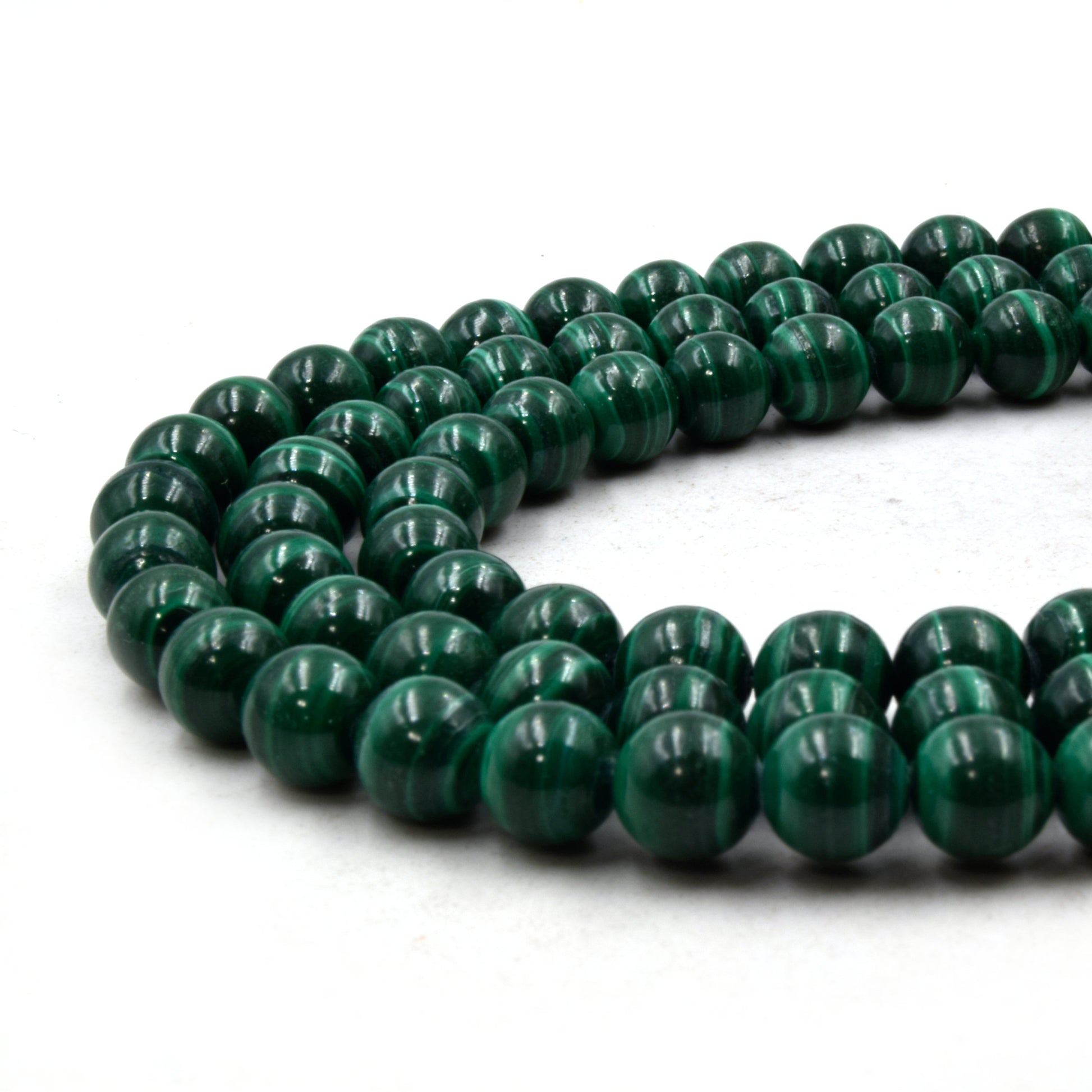 A strand of 8mm round, green malachite beads on a white background