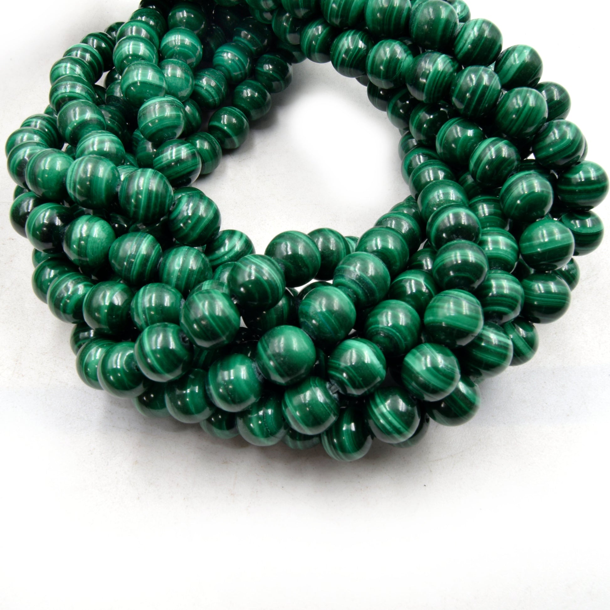 A close-up of a strand of 8mm round, green malachite beads