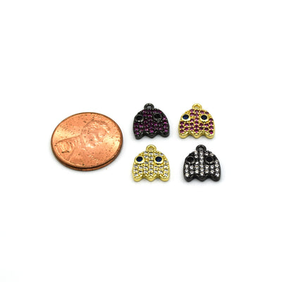A photograph showing 4 pacman ghost charms next to a penny for sizing reference. These gold and black charms are used for jewelry making