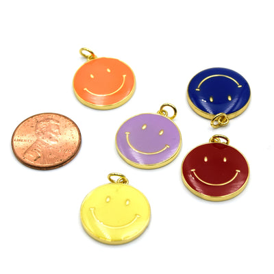 A variety of colorful enamel charms shaped like happy faces, perfect for making unique jewelry pieces. The charms are next to a penny for sizing reference.
